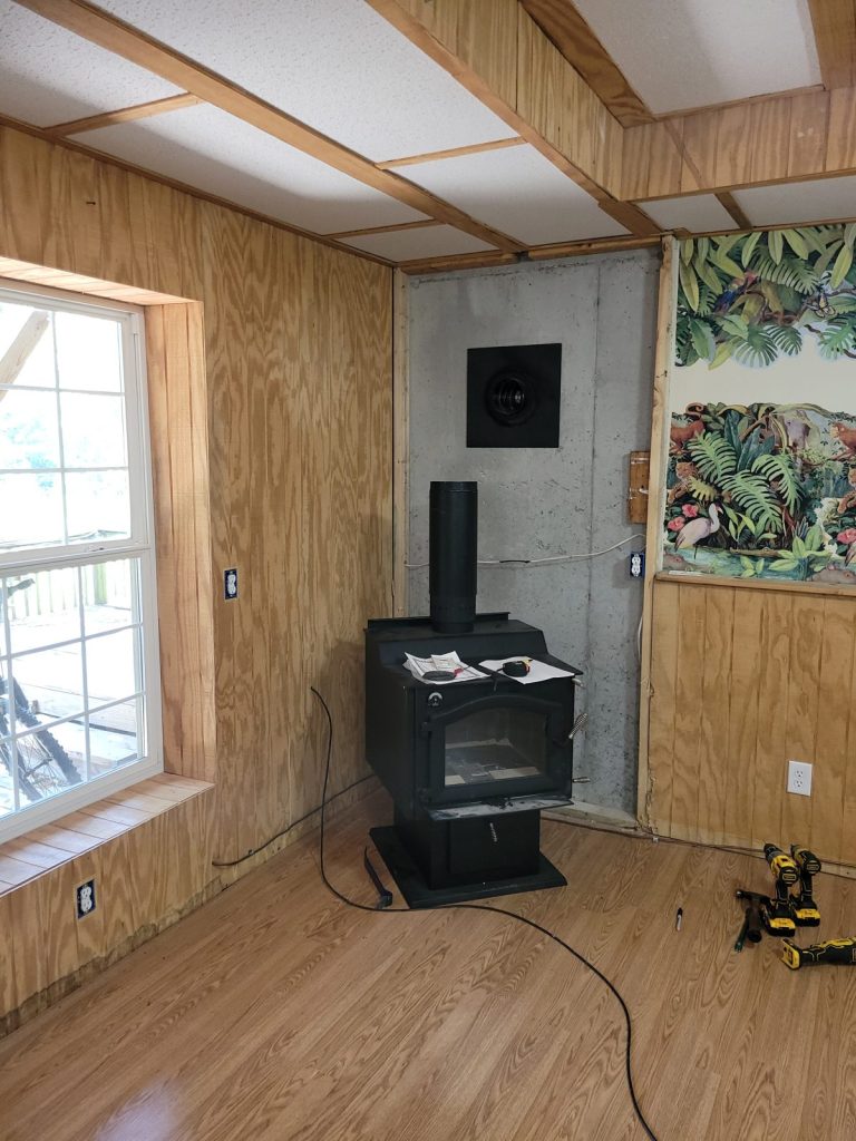 Basement corner before the wood stove project with old stove and paneling