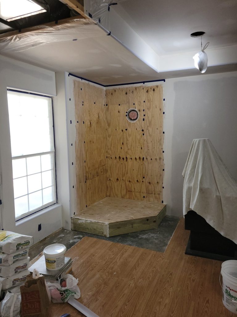 Plywood covering the hearth platform and the wall behind the stove