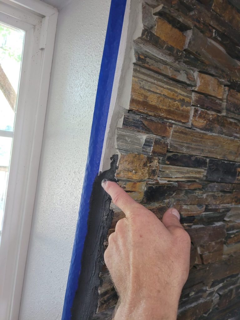 Taping off the stone wall edges before framing them with grout