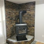 Finished wood stove on a raised tiled hearth with a slate stone wall