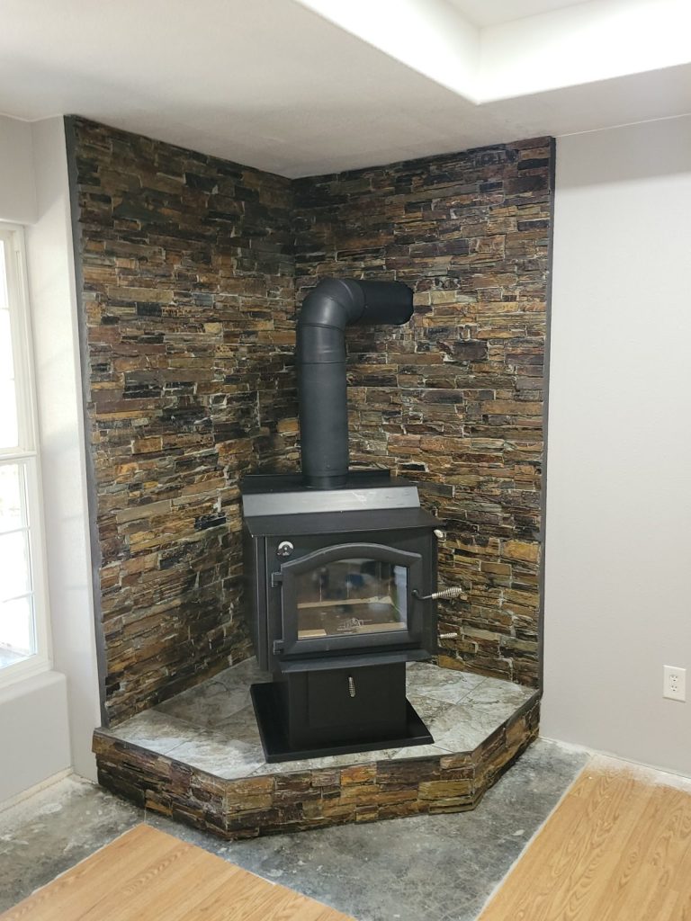 Finished wood stove on a raised tiled hearth with a slate stone wall