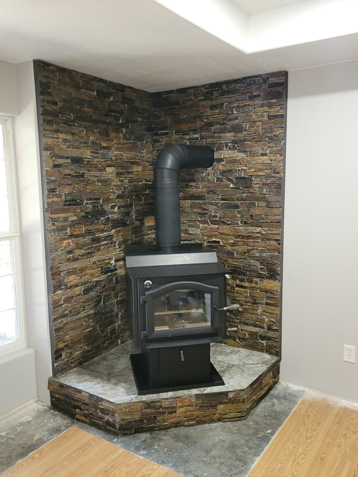 Finished wood stove on a raised tiled hearth with a slate stone wall