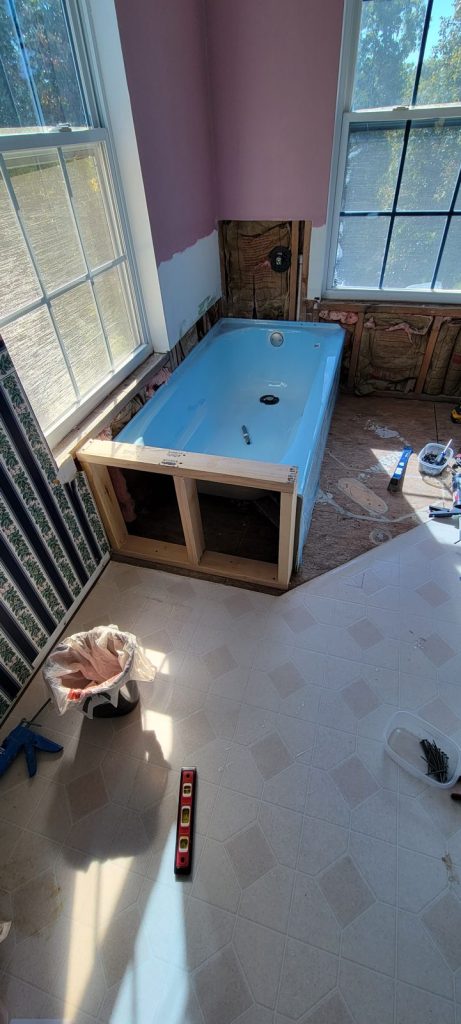 Small half wall framed to support and close in the open end of the tub